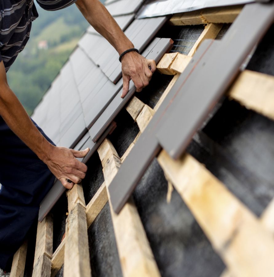 Ein Dachdecker verlegt Dachziegel